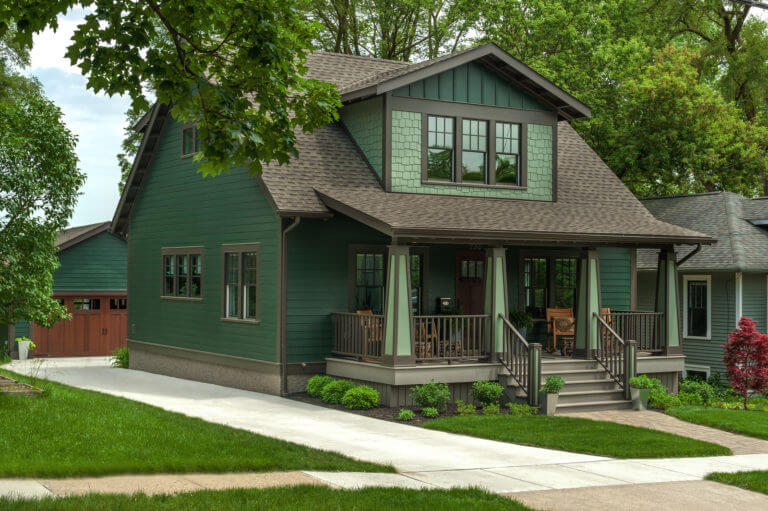 Dark sage green house with black trim and Black Window and Stairs in front and small yard in front